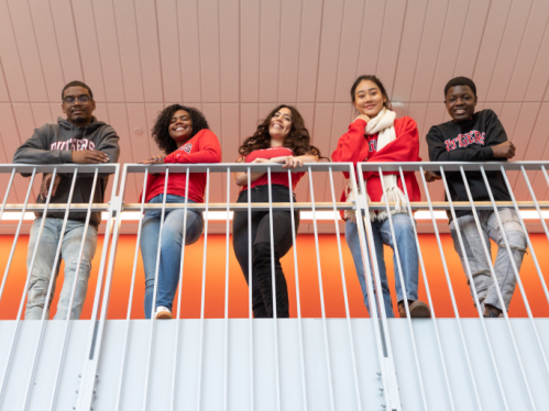 Group of Rutgers students standing against a railing smiling 