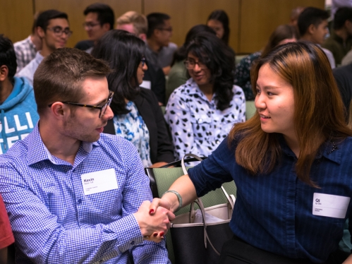 Students in group setting shaking hands